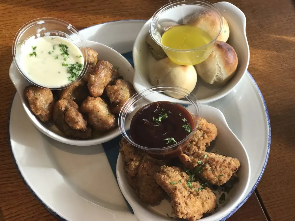 dough balls, chicken bites and garlic breaded mushrooms served in three separate bowls on one plate