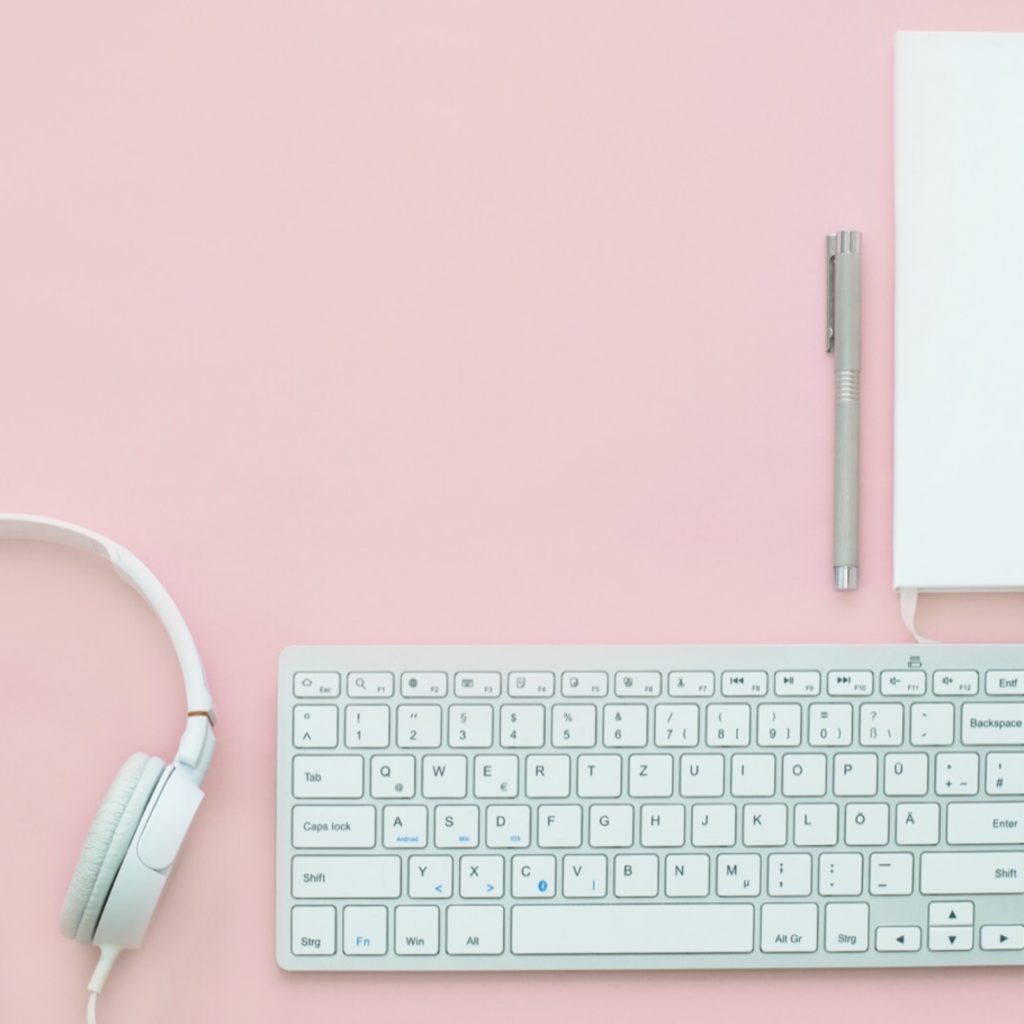 white keyboard and headphones on a pink background. 2018 blog goals