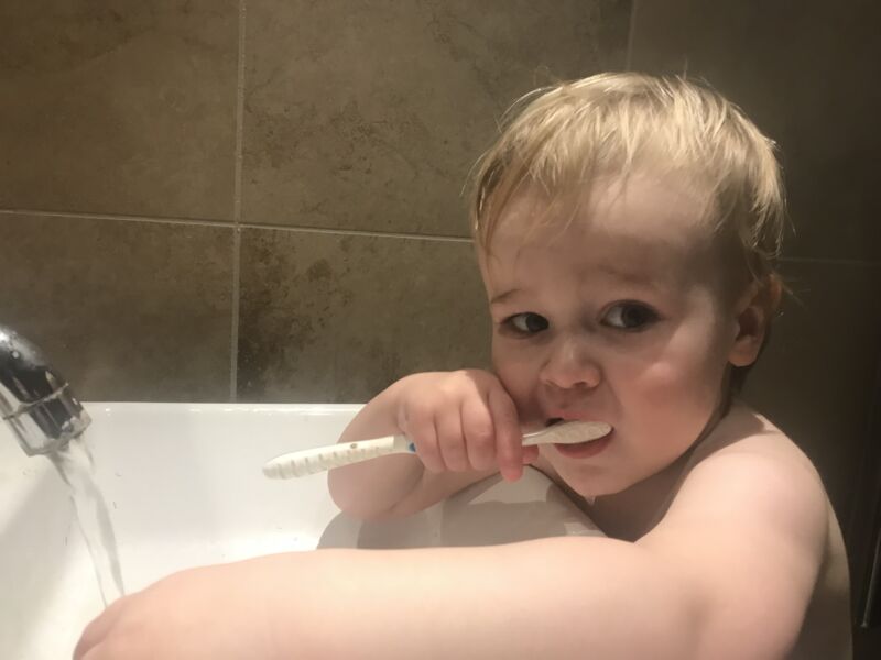 Dexter standing over sink brushing his teeth