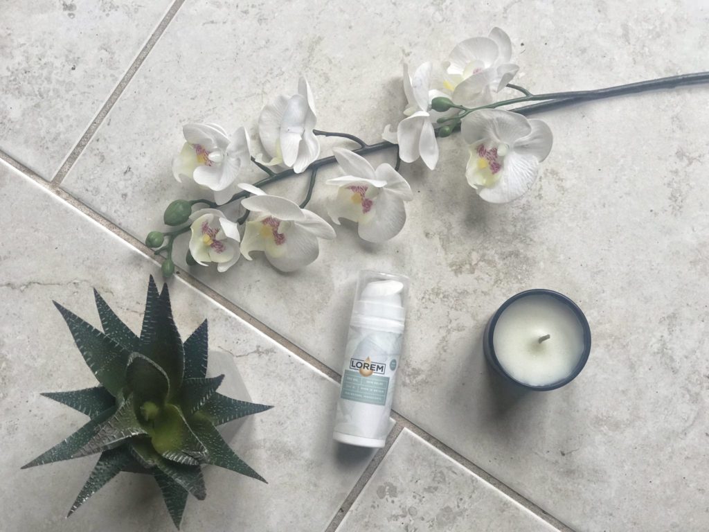 lorem cream- one of my must have pregnancy products - in a flatlay with white orchids, a candle and a cactus