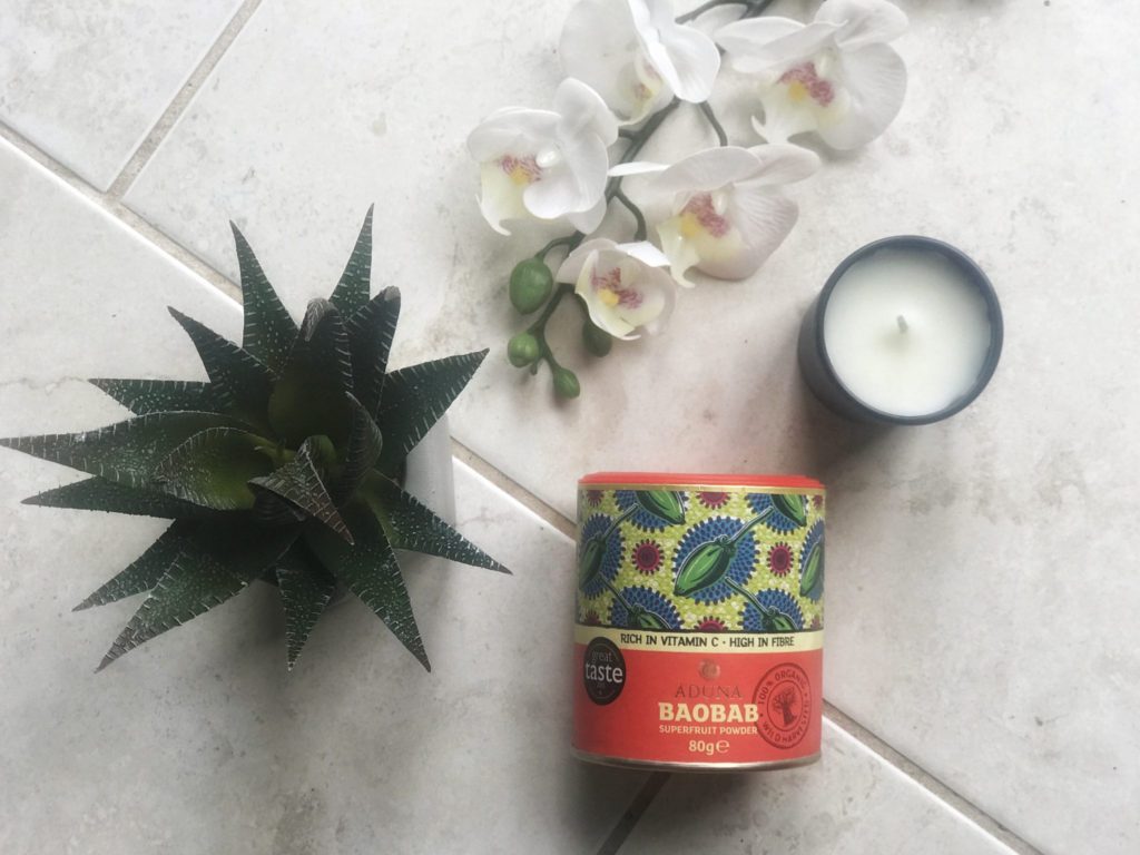 baobab powder- one of my must have pregnancy products - in a flatlay with white orchids, a candle and a cactus
