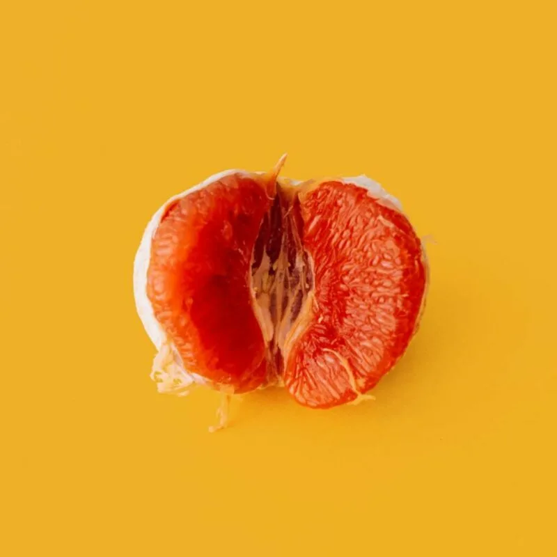 a blood red satsuma cut in half placed on an orange background