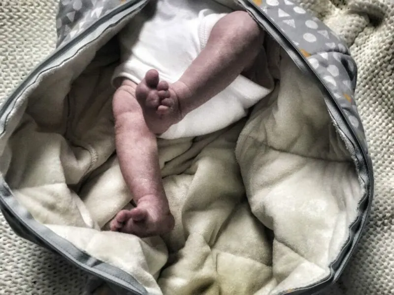 a close up of felix's legs whilst wearing the ergopouch cocoon swadlle, showing that the swaddle zips open from the bottom also