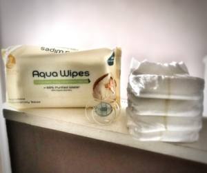 packet of aquawipes and some nappies stcaked on a shelf