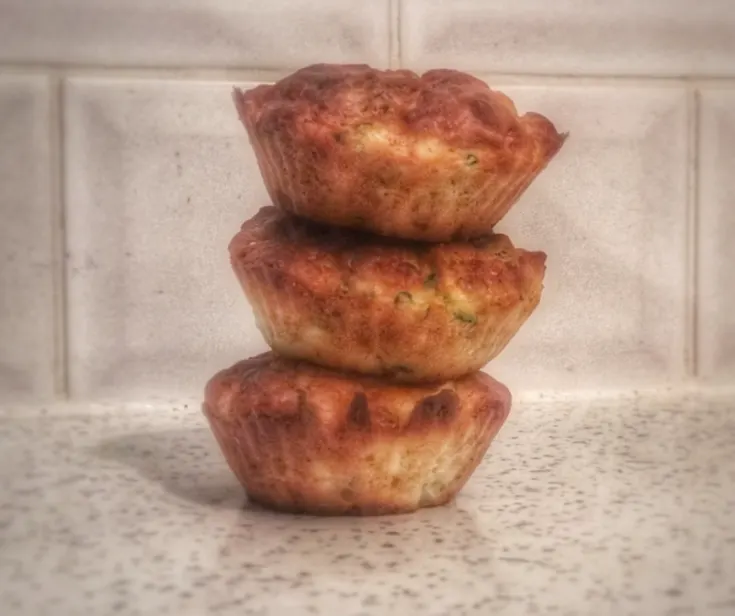 three broccoli and courgette muffins stacked neatly on top of each other