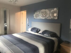our master bedroom before we moved in with blue walls and a superking bed with a grey duvet cover