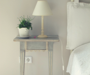 a bedside table with a lamp and a plant on it