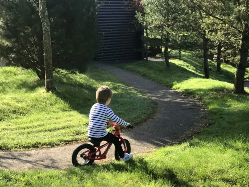 Dexter riding a red balance bike down a path outside our lodge in bluestone wales