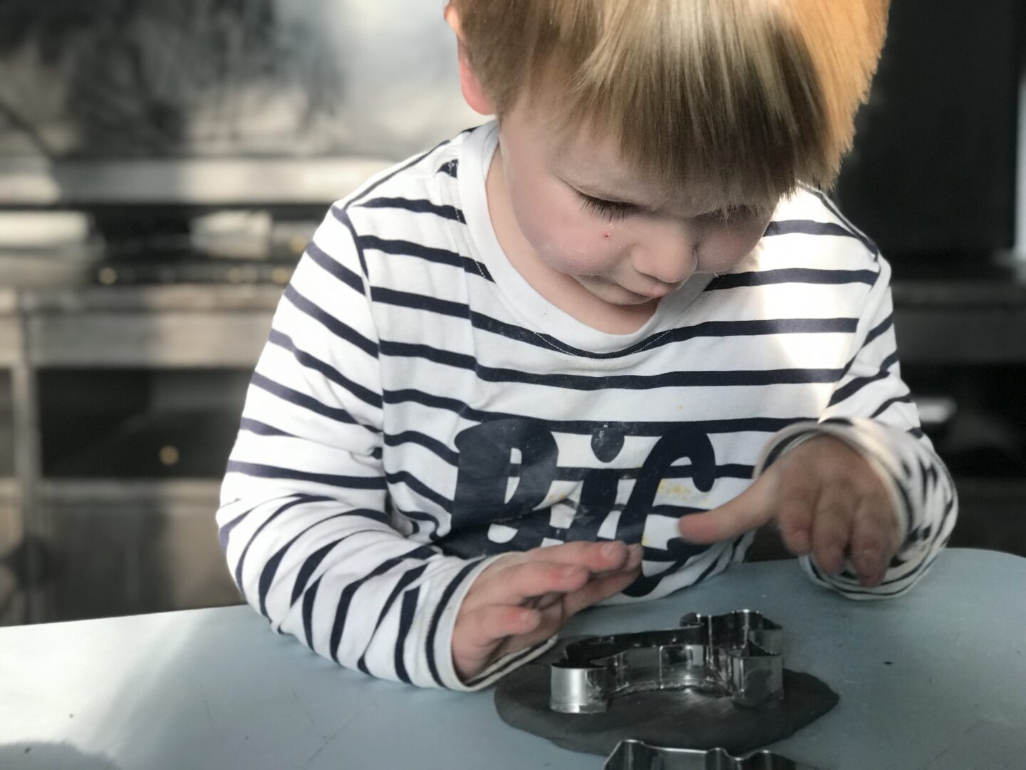 Dexter putting a cookie cutter into some black playdough that we handmade