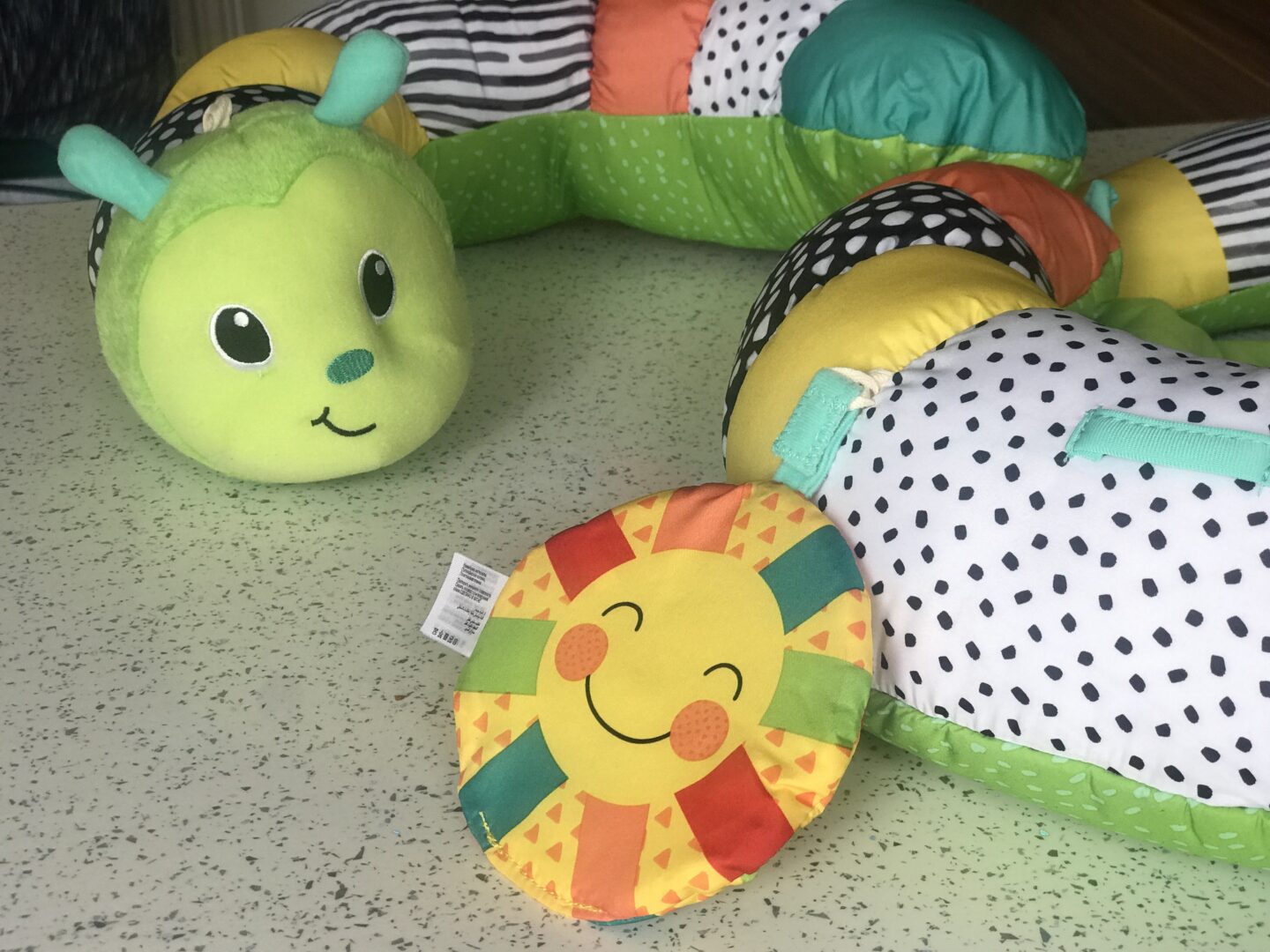 A close up of the Infantino Prop-a-Pillar tummy time support showing the crinkled sun and caterpillar's face