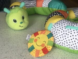 A close up of the Infantino Prop-a-Pillar tummy time support showing the crinkled sun and caterpillar's face