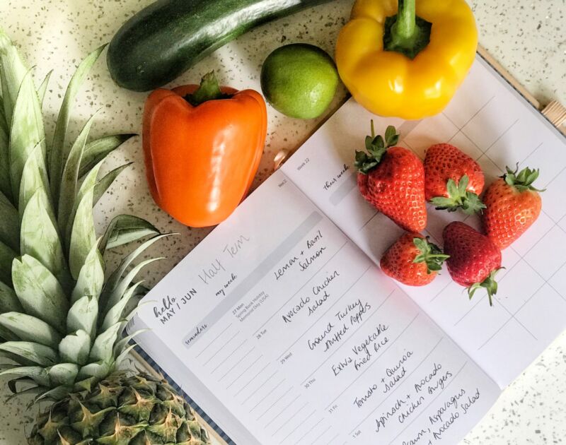 A diary with a meal plan on each day’s surrounded by brightly coloured fruit and vegetables