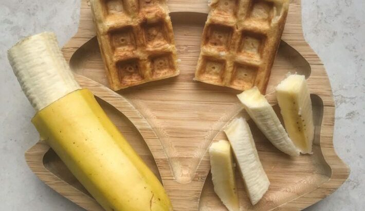 Sweet potato waffles on a bamboo bamboo plate served alongside banana
