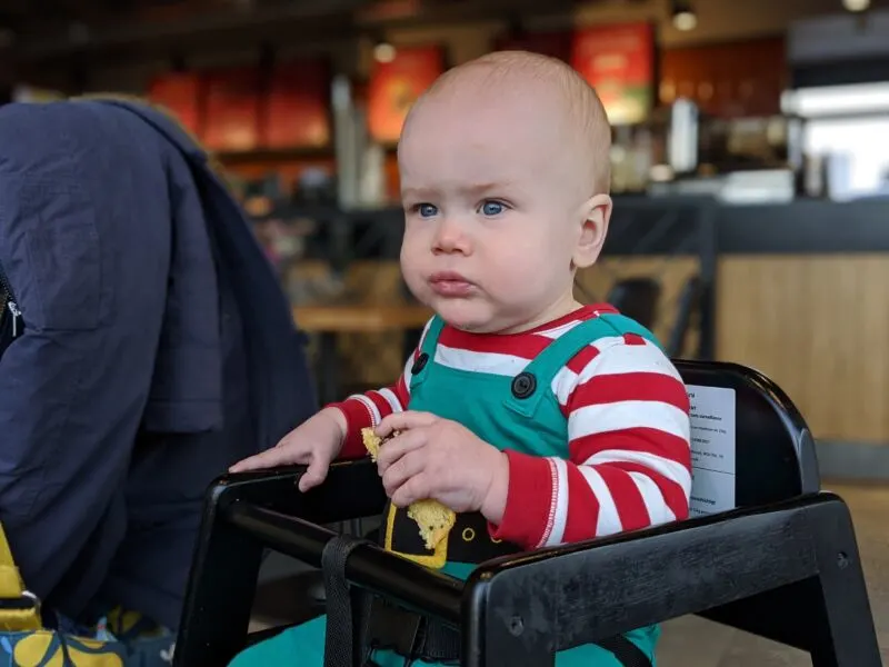 Felix wearing a Christmas outfit sat in a wooden highchair in Starbucks