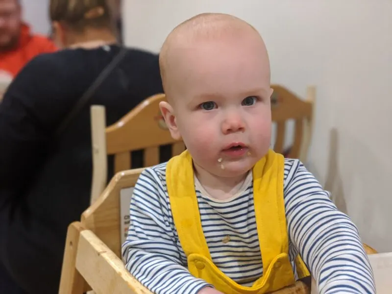 Felix wearing yellow dungarees sat in a highchair in Trafford Centre