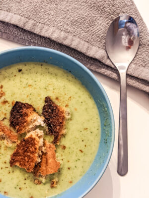 grown up portion of broccoli and stilton soup with a spoon and croutons