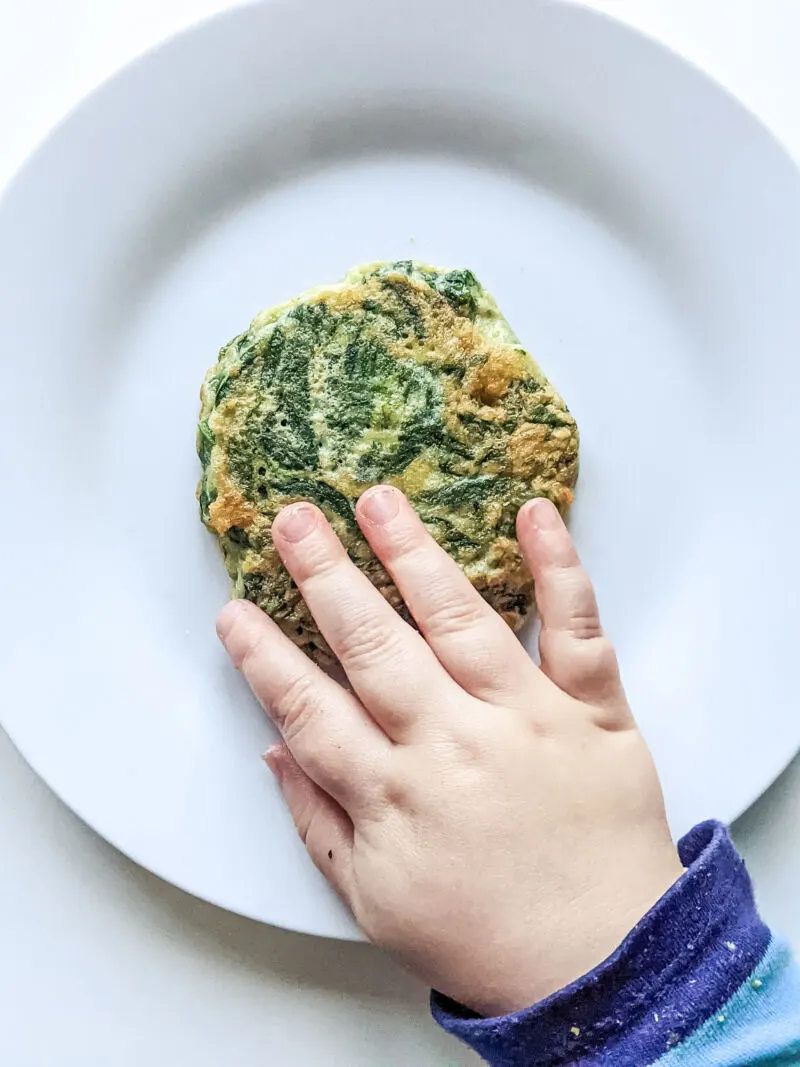 Felix touching spinach fritters baby