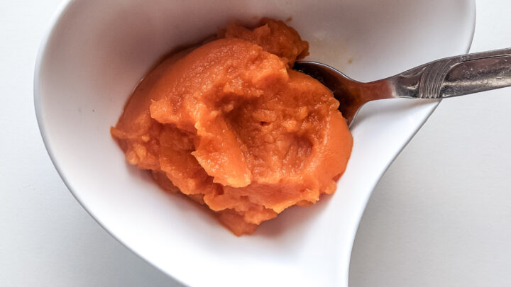sweet potato mash for babies in a heart shaped bowl with a spoon