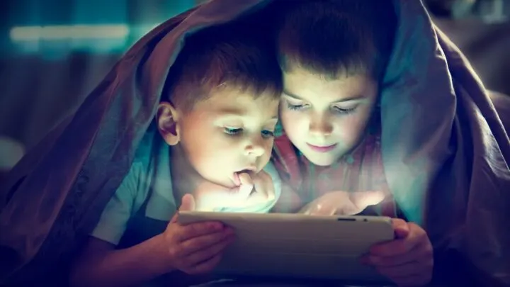 two boys watching ipad in bed