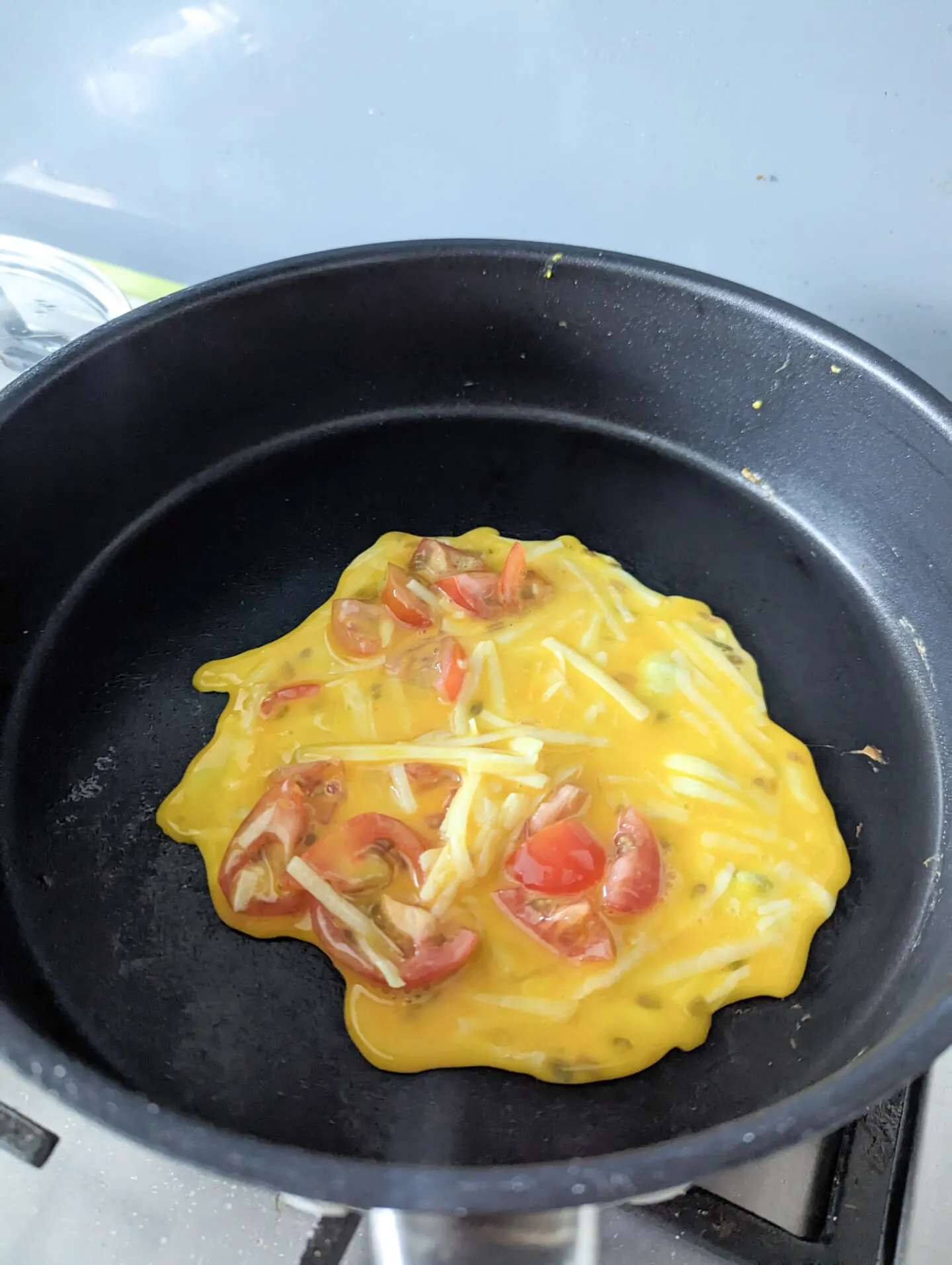 cheese and tomato omelette cooking in the pan